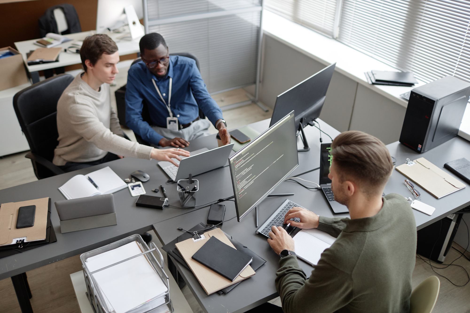 A bustling office setting with a team of professionals working together on computers, surrounded by advanced security systems and technology