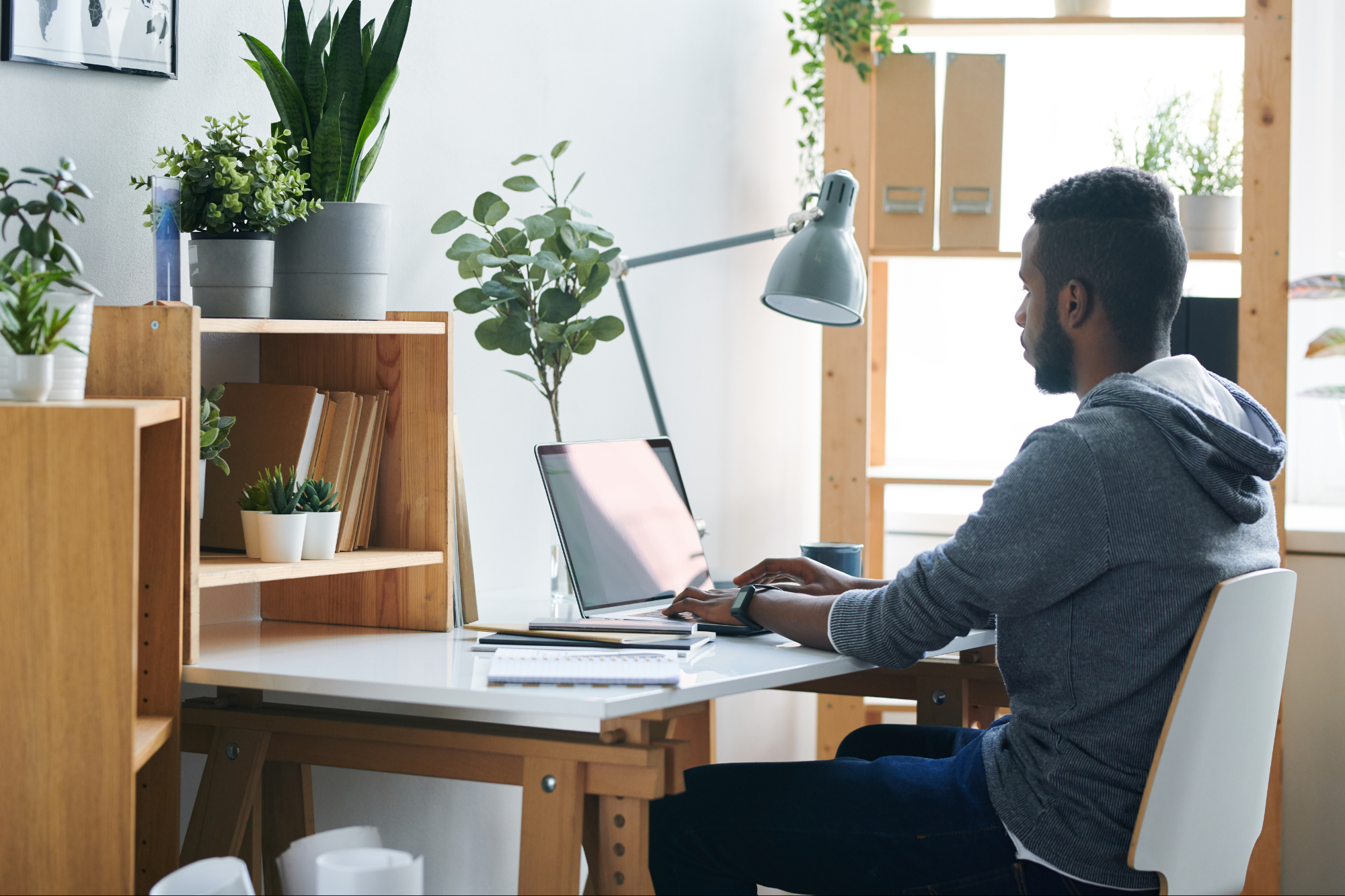 A small business owner working on a laptop while surrounded by various remote work technology, such as a computer, phone, and tablet