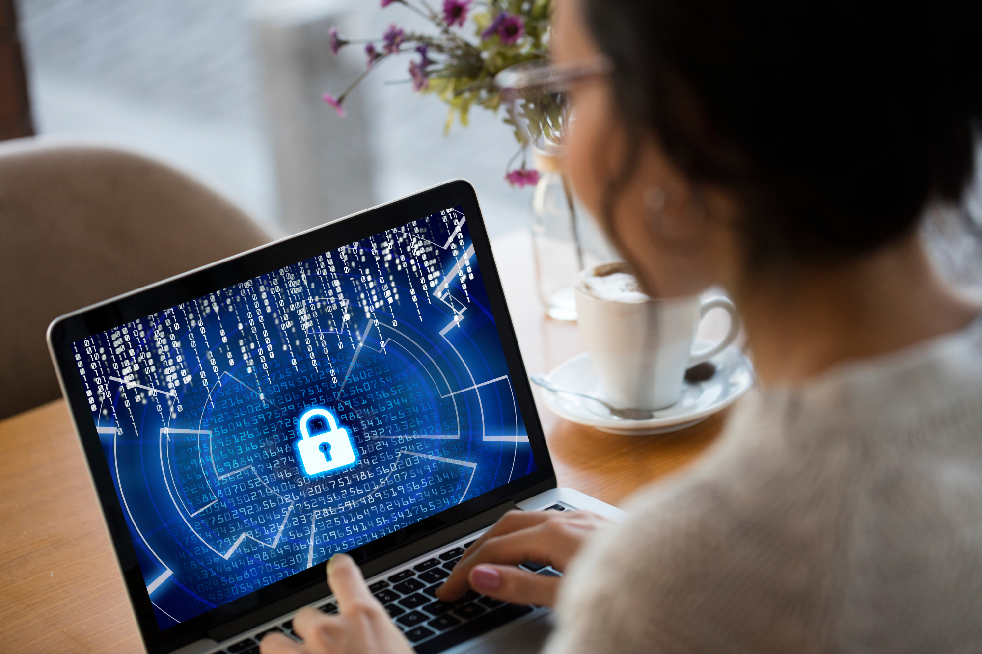 A small business owner working on a laptop in a remote location, with a secure lock icon and shield symbolizing cybersecurity