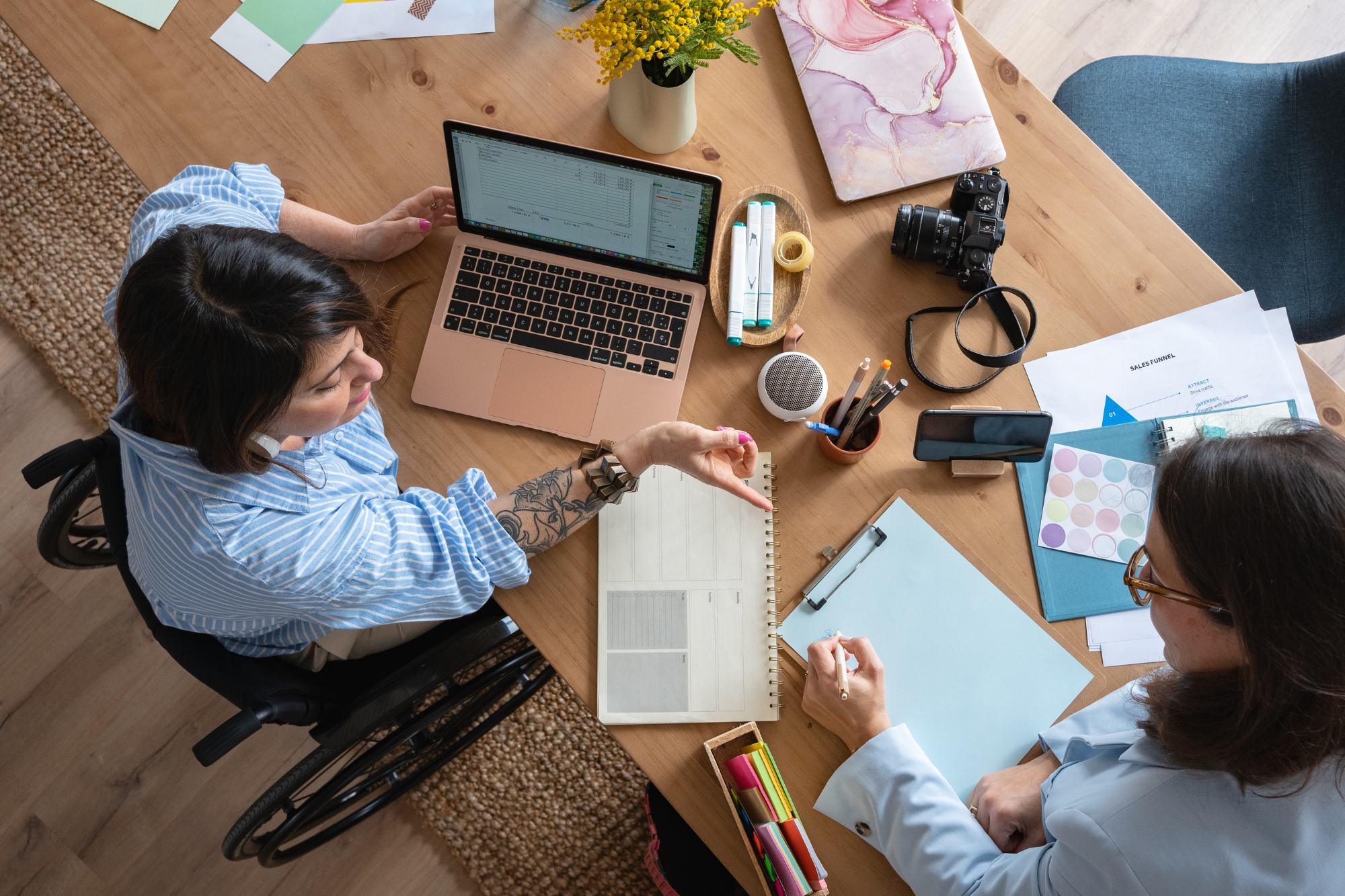A small business owner working on a laptop while a remote team collaborates virtually. Servers and technology equipment are shown in the background