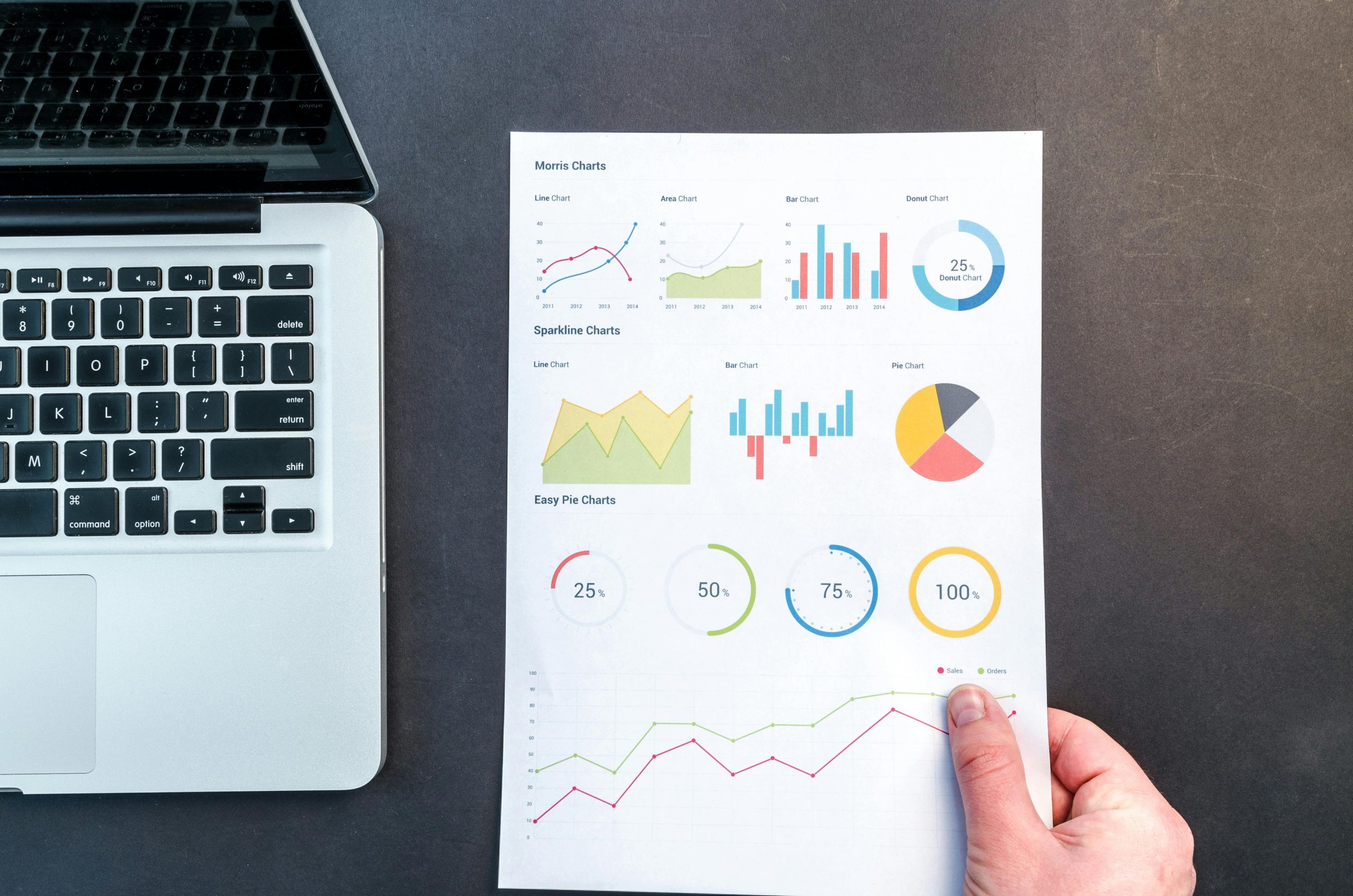A group of diverse small business owners collaborate around a table, surrounded by charts and graphs, using data analytics tools on their laptops